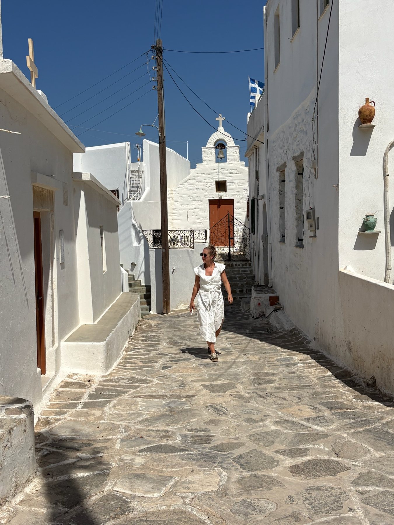 Tess walking through a whitewashed Greek street